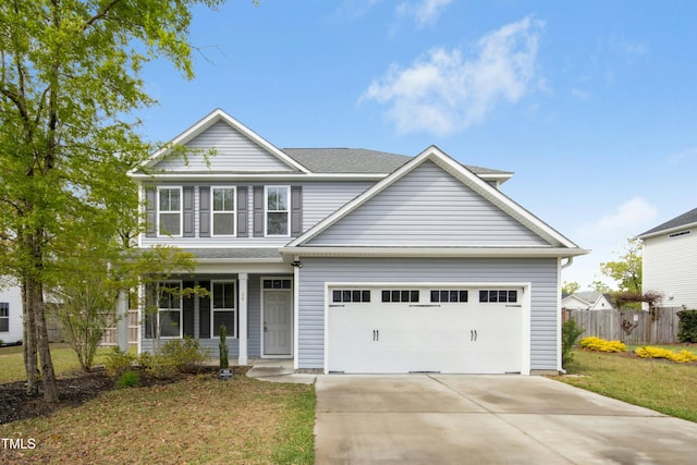 traditional-style home featuring a garage, a front yard, driveway, and fence
