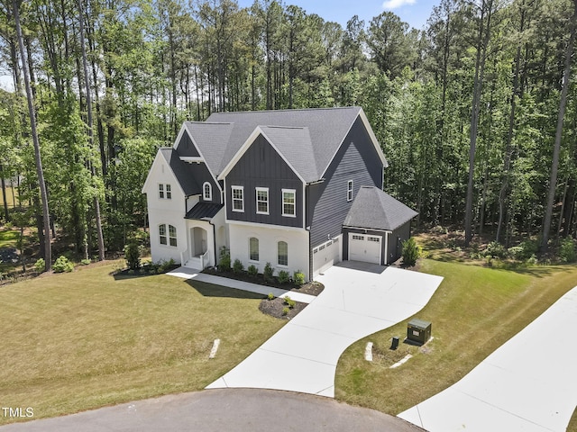 view of front of house with board and batten siding, a garage, concrete driveway, and a front lawn
