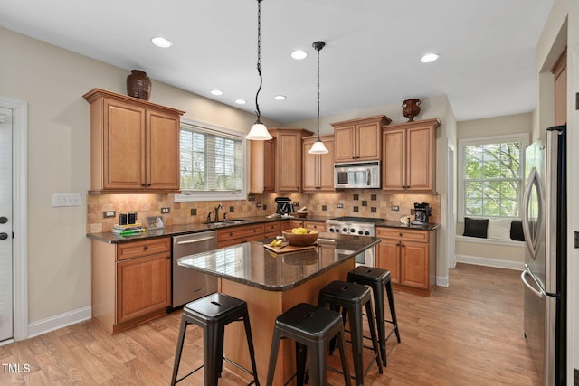 kitchen with light wood finished floors, a breakfast bar, a wealth of natural light, and stainless steel appliances