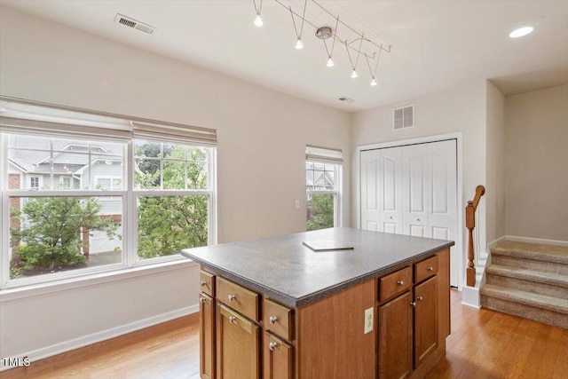 615 Carlton Commons Ln, Cary, NC 27519 - kitchen with baseboards, dark countertops, a center island, light wood-style floors, and brown cabinetry