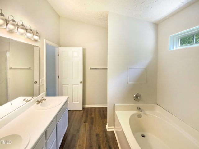 5828 Brambleton Ave, Raleigh, NC 27610 - full bathroom with a garden tub, double vanity, wood finished floors, a sink, and a textured ceiling
