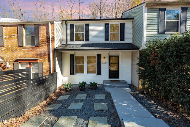 view of front of home with brick siding, covered porch, and fence