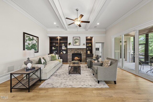 living area with ornamental molding, a ceiling fan, a fireplace, wood finished floors, and beam ceiling