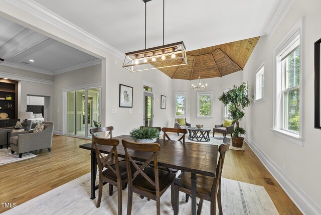 dining room featuring light wood-type flooring, a chandelier, baseboards, and crown molding