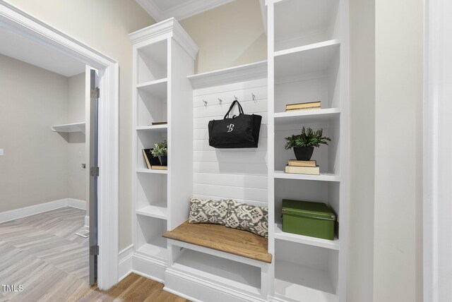 mudroom with wood finished floors, built in shelves, and baseboards