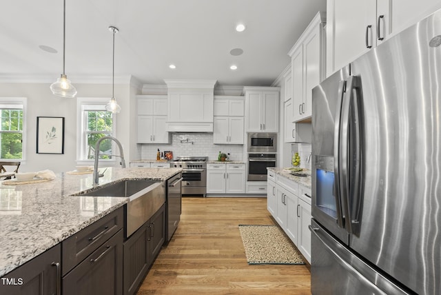kitchen featuring appliances with stainless steel finishes, a sink, crown molding, white cabinetry, and recessed lighting
