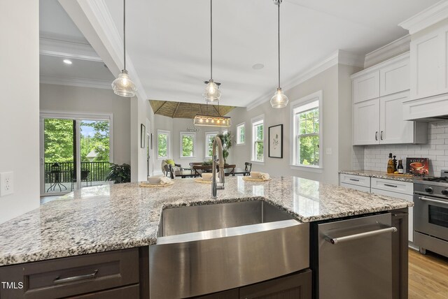kitchen featuring a sink, stainless steel appliances, crown molding, tasteful backsplash, and white cabinets
