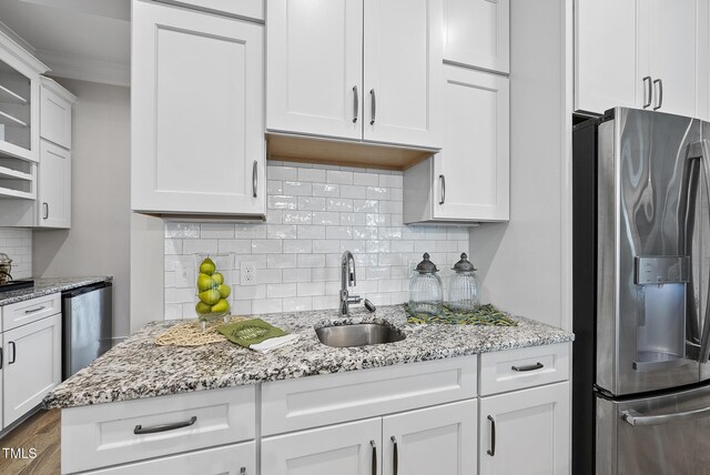 kitchen with stainless steel fridge with ice dispenser, a sink, crown molding, decorative backsplash, and white cabinets
