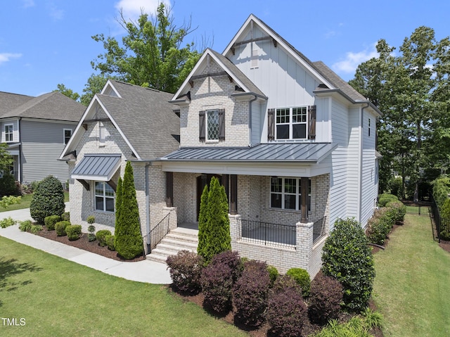 craftsman inspired home featuring a standing seam roof, board and batten siding, a front yard, and brick siding