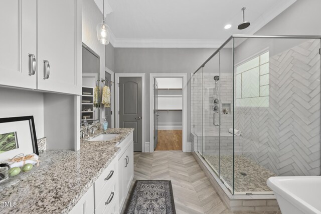 bathroom with a shower stall, crown molding, vanity, a walk in closet, and a soaking tub