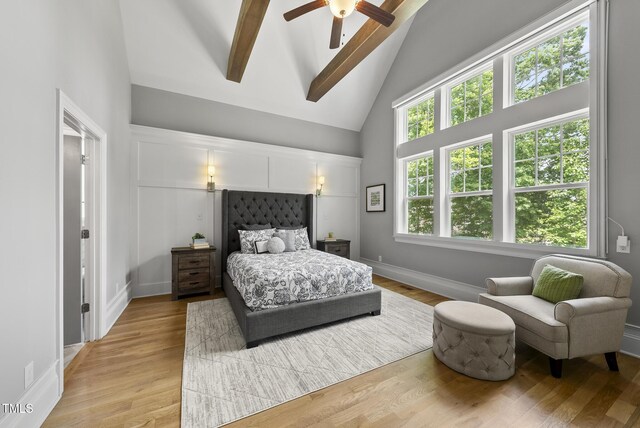 bedroom featuring high vaulted ceiling, beam ceiling, light wood-type flooring, baseboards, and a ceiling fan