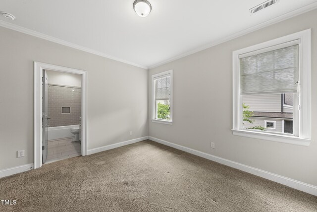 unfurnished bedroom with crown molding, carpet floors, baseboards, and ensuite bathroom