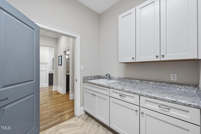 washroom featuring a sink, baseboards, and light wood finished floors