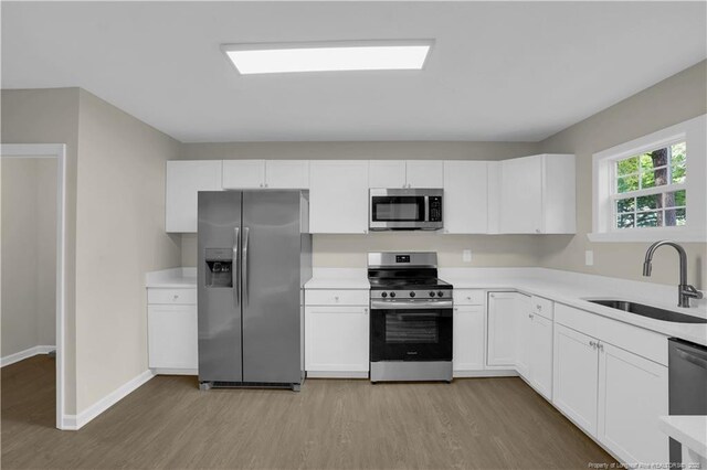 213 Judd St, Fayetteville, NC 28305 - kitchen featuring appliances with stainless steel finishes, a sink, white cabinetry, and light wood-type flooring