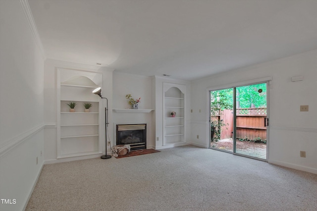 unfurnished living room with built in shelves, carpet, ornamental molding, a fireplace with flush hearth, and baseboards