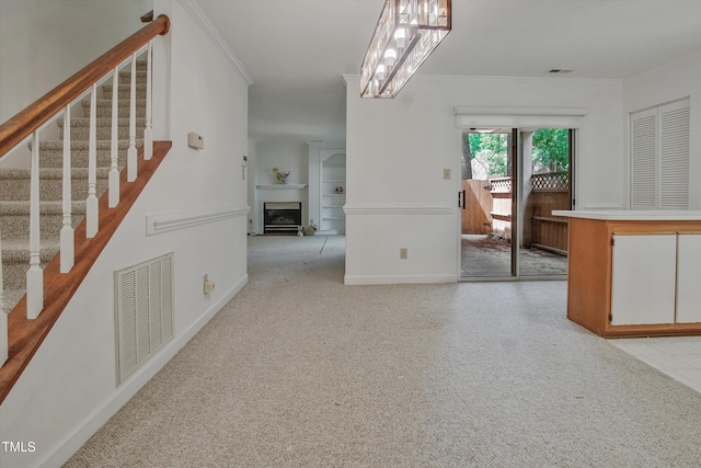 empty room with stairway, baseboards, a fireplace, built in features, and crown molding