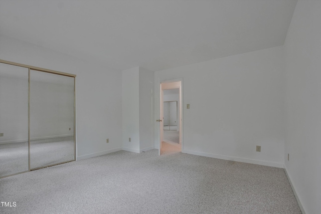 unfurnished bedroom featuring light colored carpet, baseboards, and a closet