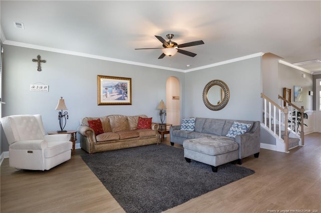 living room with wood finished floors, arched walkways, crown molding, ceiling fan, and baseboards