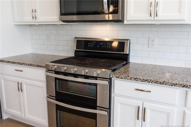 kitchen featuring stainless steel appliances, light stone counters, white cabinetry, and decorative backsplash