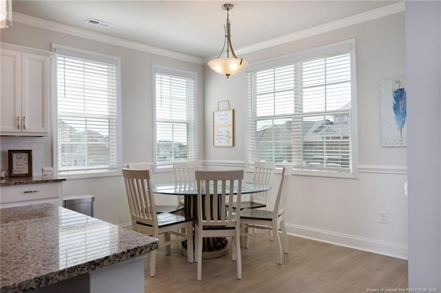 dining space with light wood-type flooring, ornamental molding, and baseboards