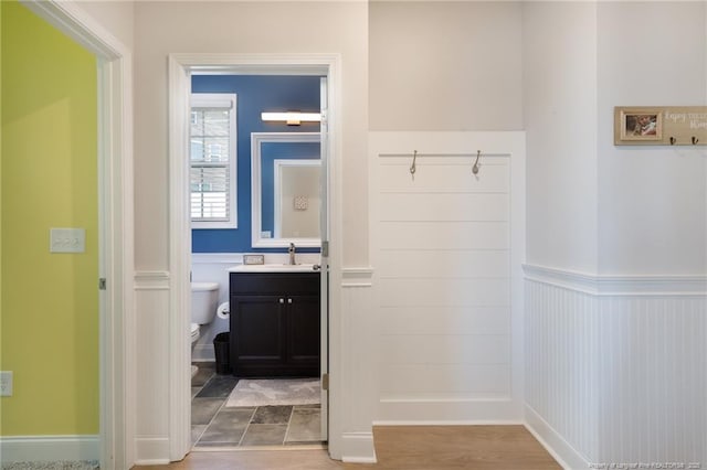 bathroom with a wainscoted wall, toilet, and vanity
