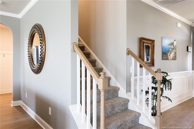 stairs featuring crown molding, wood finished floors, and arched walkways