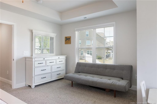 living area featuring light colored carpet, a raised ceiling, and baseboards