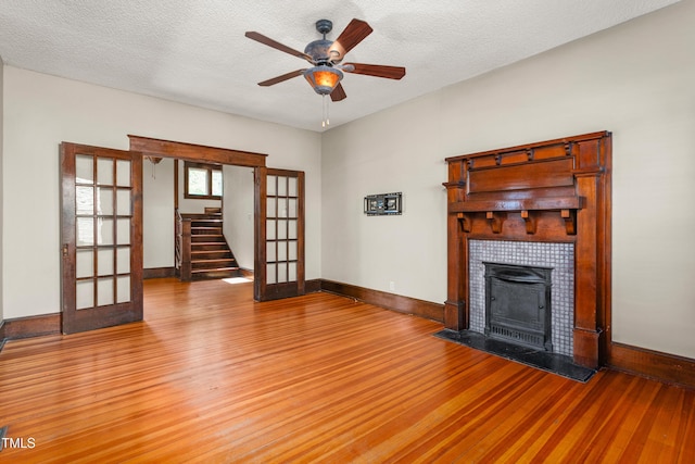 104 E Wilson St, Mebane, NC 27302 - unfurnished living room with french doors, light wood-style floors, a ceiling fan, a fireplace, and a textured ceiling