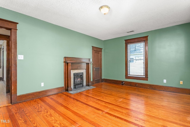 104 E Wilson St, Mebane, NC 27302 - unfurnished living room featuring light wood-style flooring, a premium fireplace, baseboards, and a textured ceiling