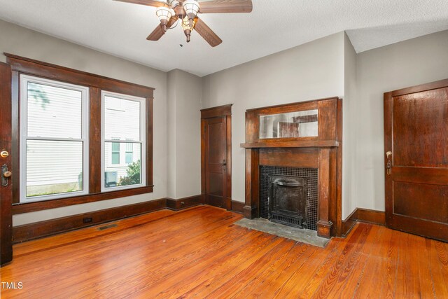104 E Wilson St, Mebane, NC 27302 - unfurnished living room with light wood-style floors, plenty of natural light, a ceiling fan, and a fireplace with flush hearth