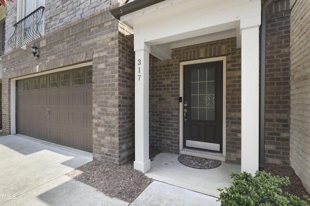 entrance to property featuring an attached garage and brick siding