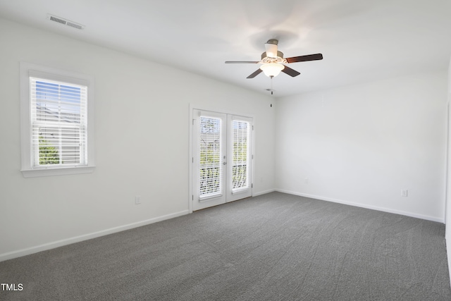 empty room with baseboards, dark colored carpet, visible vents, and ceiling fan