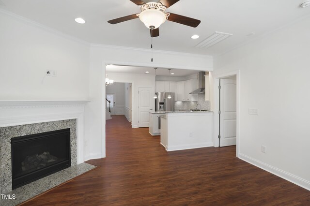 unfurnished living room featuring ornamental molding, a sink, dark wood-style flooring, and ceiling fan with notable chandelier