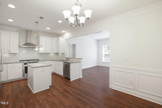 kitchen with wall chimney exhaust hood, a peninsula, decorative backsplash, a kitchen island, and appliances with stainless steel finishes