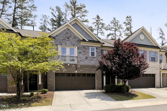 townhome / multi-family property featuring driveway, stone siding, brick siding, an attached garage, and a balcony
