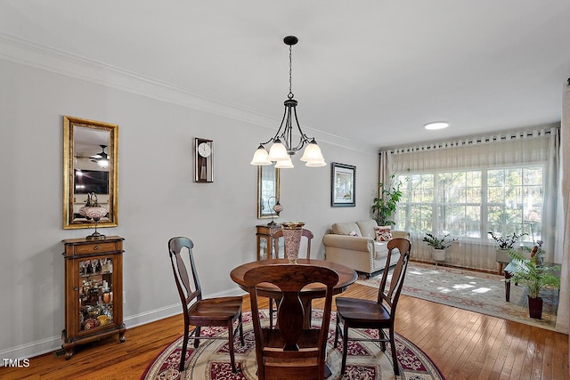dining area featuring a chandelier, hardwood / wood-style flooring, ornamental molding, and baseboards
