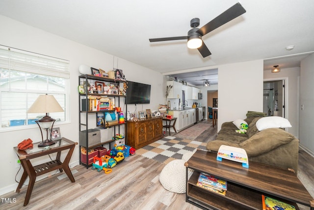 living room with a ceiling fan, wood finished floors, and baseboards
