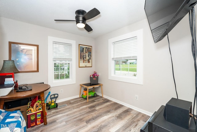 playroom featuring a ceiling fan, baseboards, light wood-style flooring, and plenty of natural light