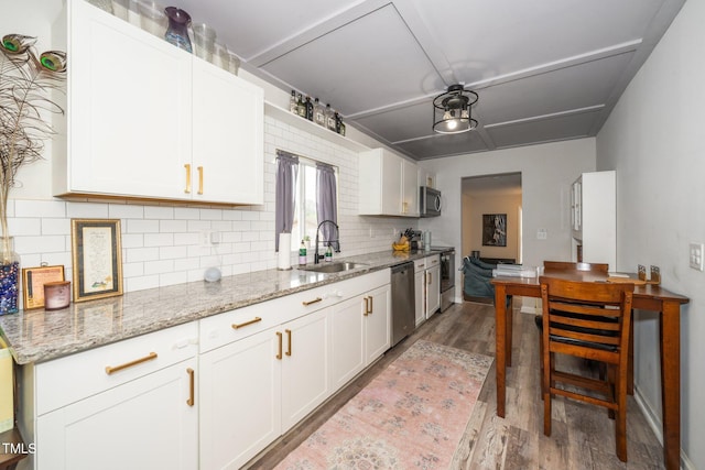 kitchen with white cabinets, appliances with stainless steel finishes, wood finished floors, and tasteful backsplash