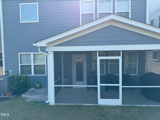 rear view of property featuring a sunroom, cooling unit, and a yard