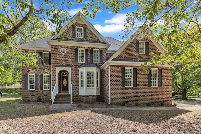 georgian-style home with brick siding, roof with shingles, and entry steps