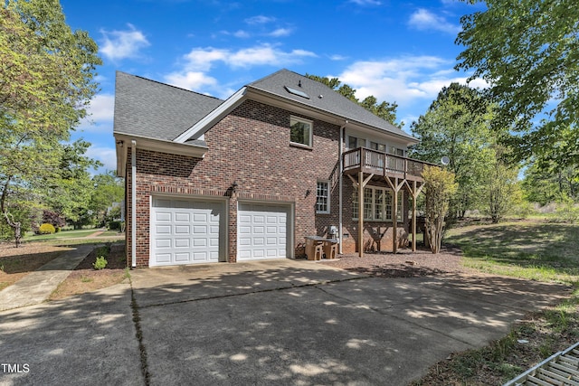 view of front of home with driveway, a deck, a shingled roof, a garage, and brick siding
