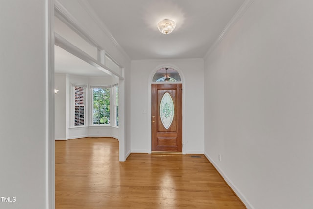 entryway featuring baseboards, light wood-style floors, and ornamental molding