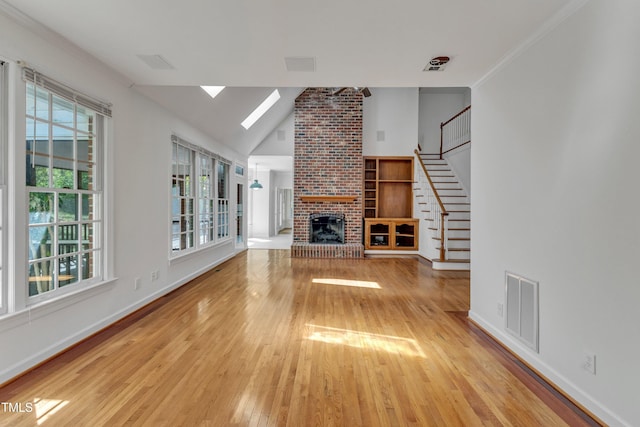 unfurnished living room with stairway, hardwood / wood-style floors, baseboards, a brick fireplace, and visible vents