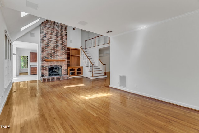 unfurnished living room featuring light wood finished floors, baseboards, visible vents, a skylight, and a fireplace
