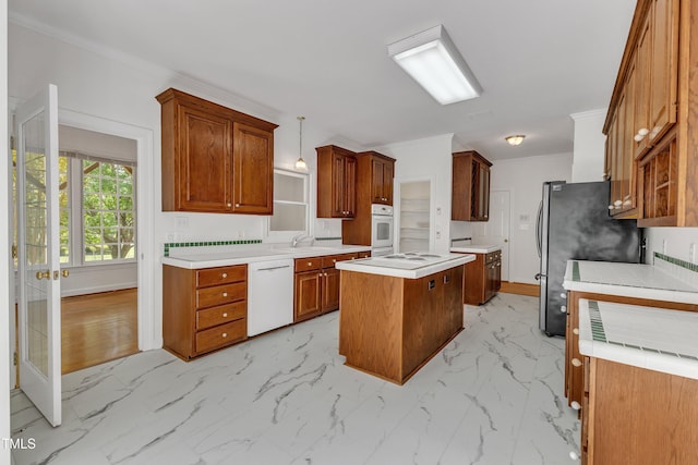 kitchen with a sink, white appliances, light countertops, baseboards, and a kitchen island