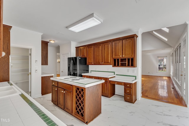 kitchen featuring black refrigerator with ice dispenser, light countertops, marble finish floor, and a center island