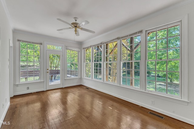 unfurnished sunroom featuring baseboards, hardwood / wood-style flooring, visible vents, and crown molding