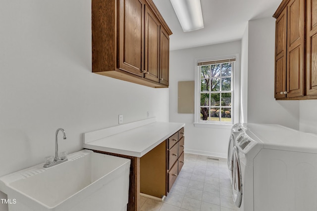 washroom featuring washer and clothes dryer, light tile patterned floors, a sink, baseboards, and cabinet space