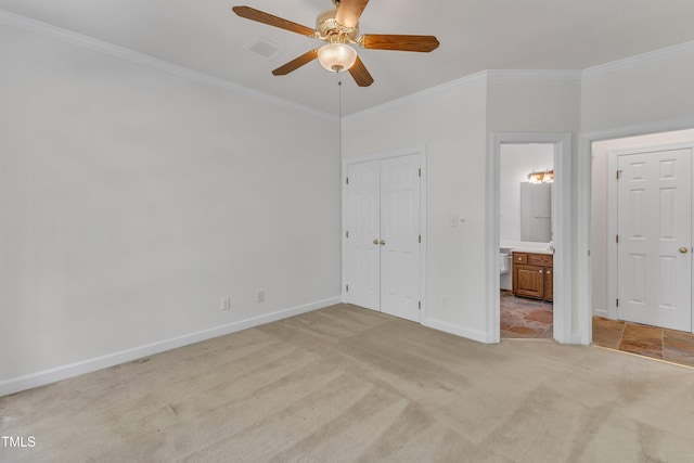 unfurnished bedroom featuring light carpet, visible vents, baseboards, crown molding, and connected bathroom